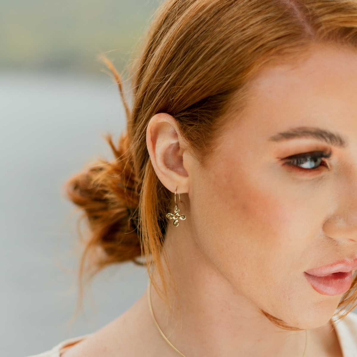 Side view of a pretty girl wearing golden celtic knot earrings