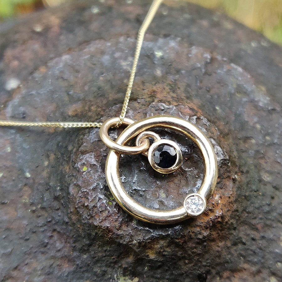 Solasta gold, diamond and sapphire necklace on a stone background.