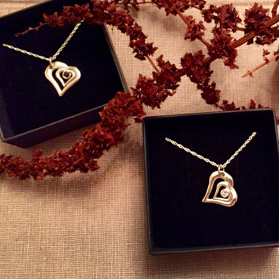 Two heart gold and diamond necklaces in display boxes.