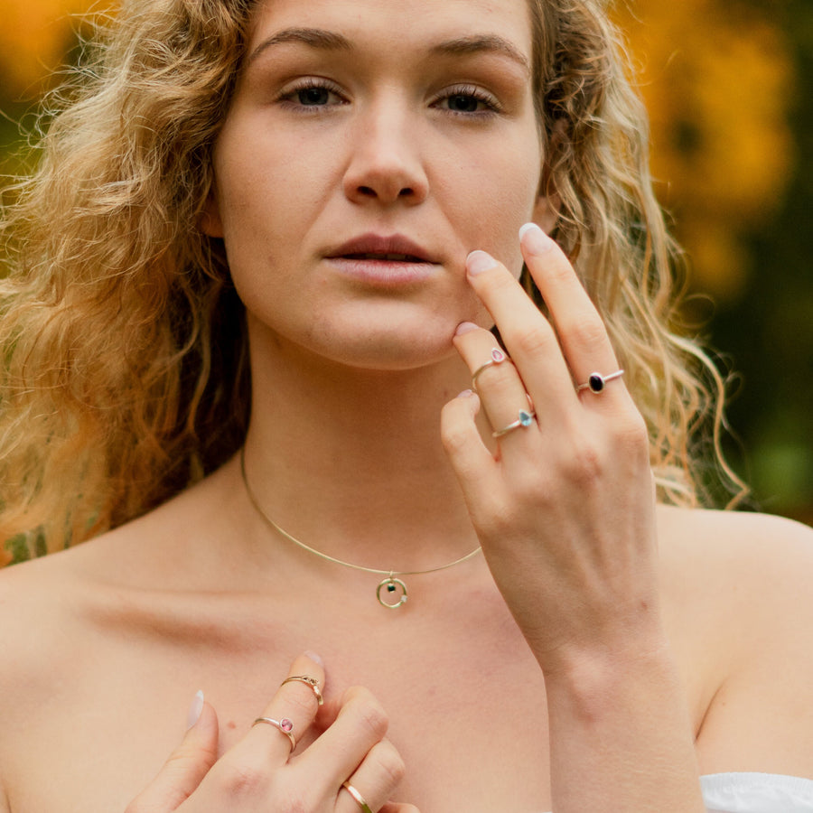 Front View of a model wearing a Solasta Omega Diamond and Sapphire Gold Necklace along with gold and silver rings