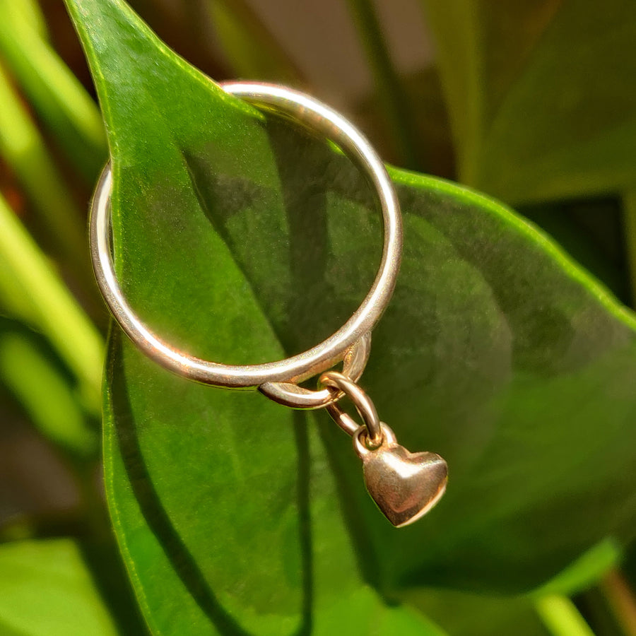 Solid Gold Heart Charm Ring on a leaf