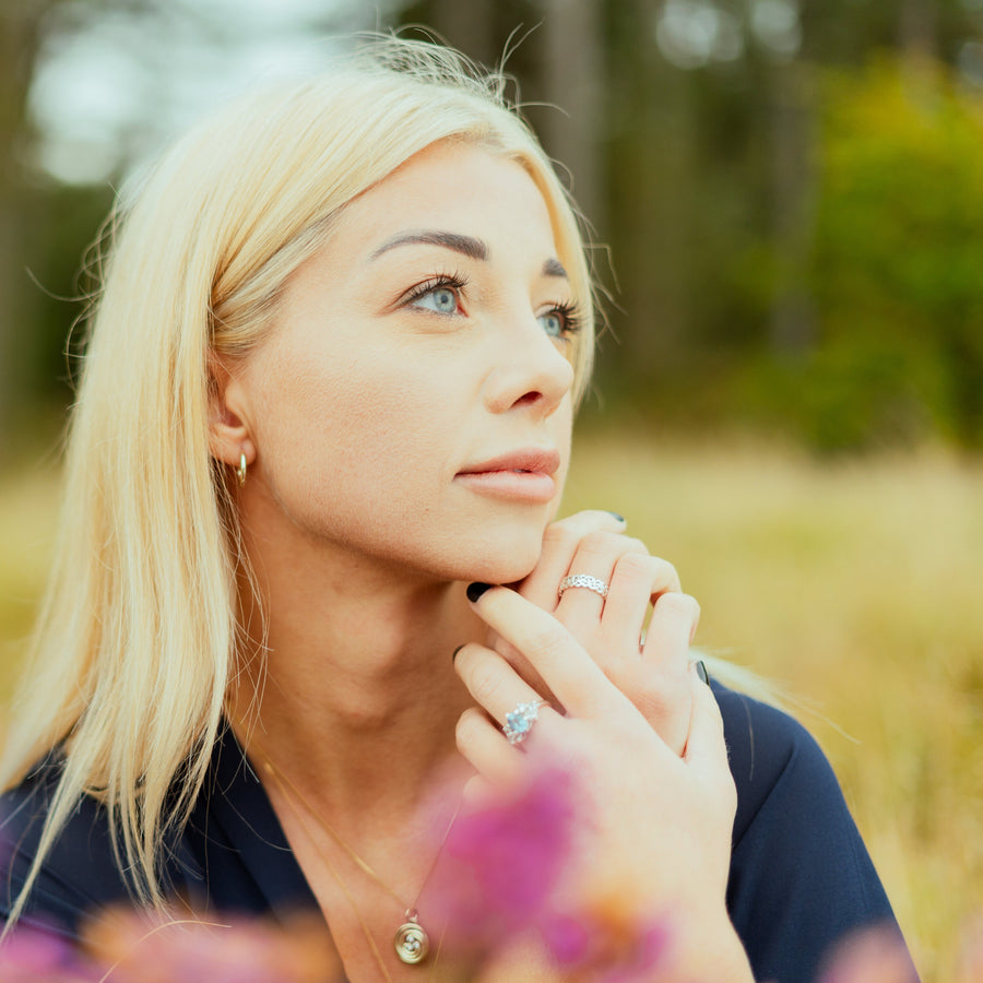 Model wearing gold necklace and silver rings.