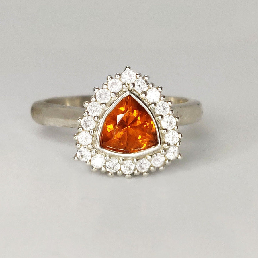 Front view of atrillion cut citrine and white sapphire halo cluster pave ring on a white background.