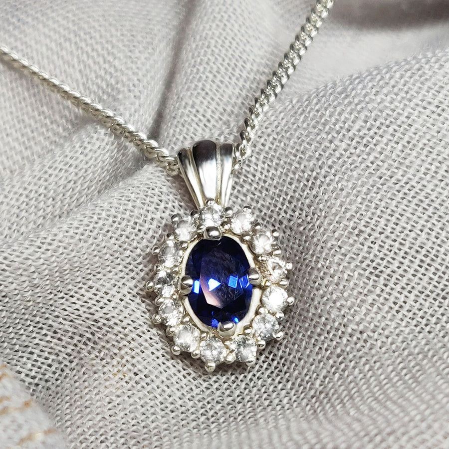 Blue and white sapphire cluster necklace on a cloth background.