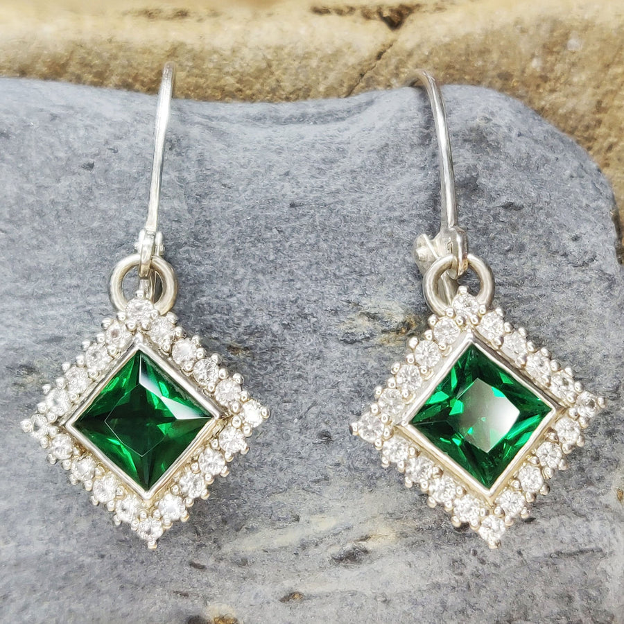 Princess Cut Emerald and Diamond Halo Earrings on a Slate Background
