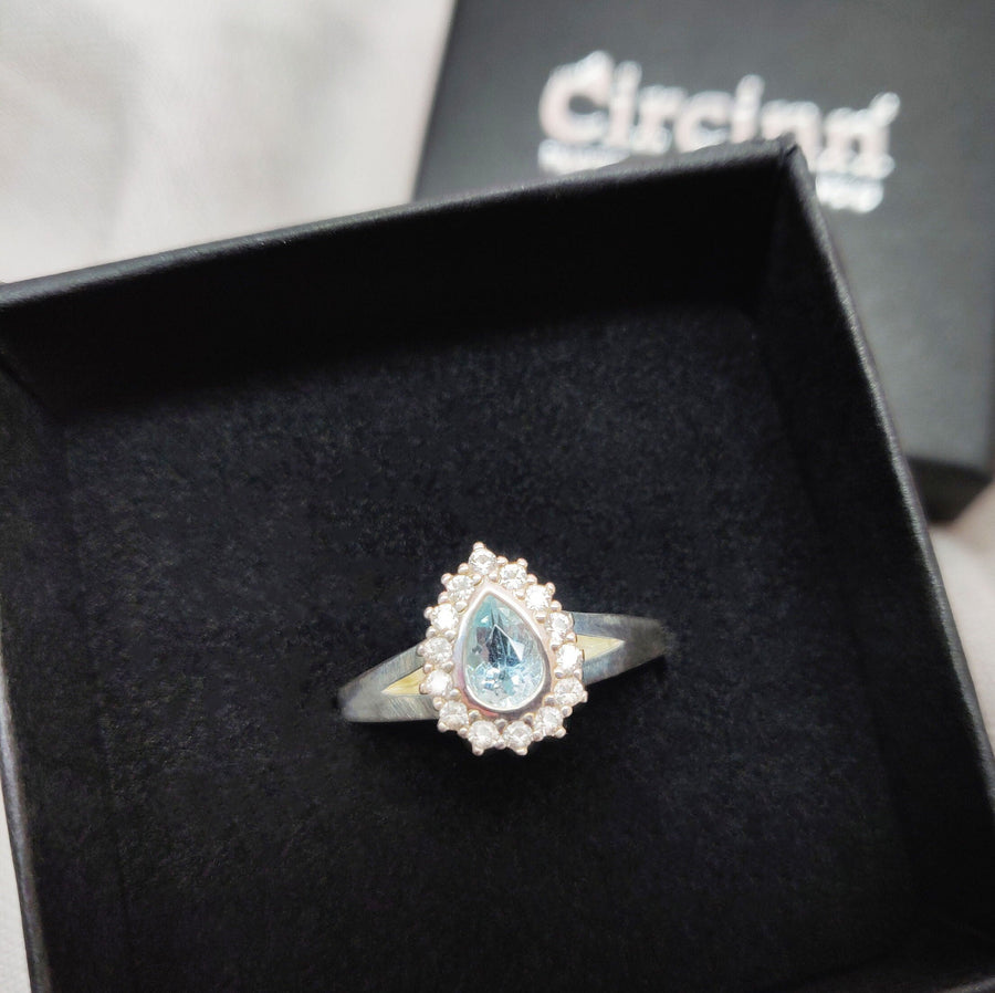 Pear cut aquamarine and white sapphire halo cluster ring in a branded Circinn ring box.