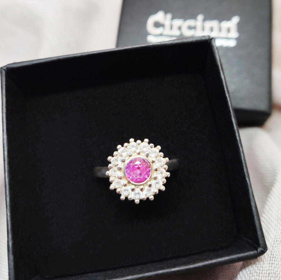 Top view of a pink and white sapphire pave cluster halo ring in a branded Circinn ring box.