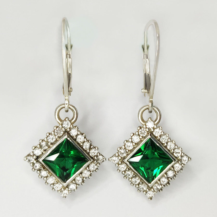 Princess Cut Emerald and Diamond Halo Earrings on a white background.