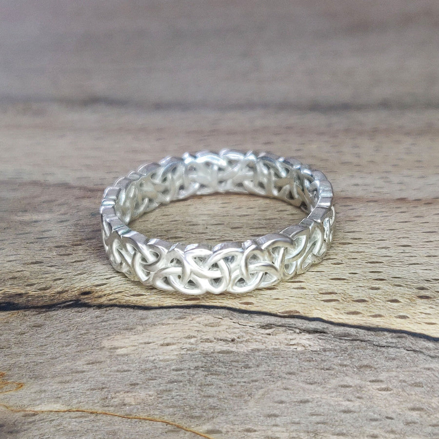 Ladies Triquetra Pattern Celtic Knot Wedding Ring on a wooden background.