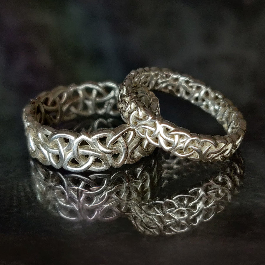 Ladies & Gents Triquetra Pattern Celtic Knot Wedding Rings on a black background.