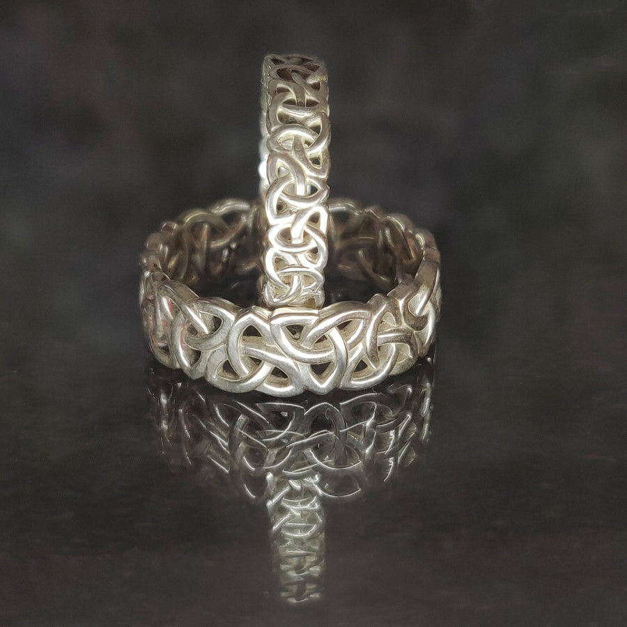 Ladies and Gents Triquetra Celtic Knot Viking Wedding Ring on a Reflective Background.