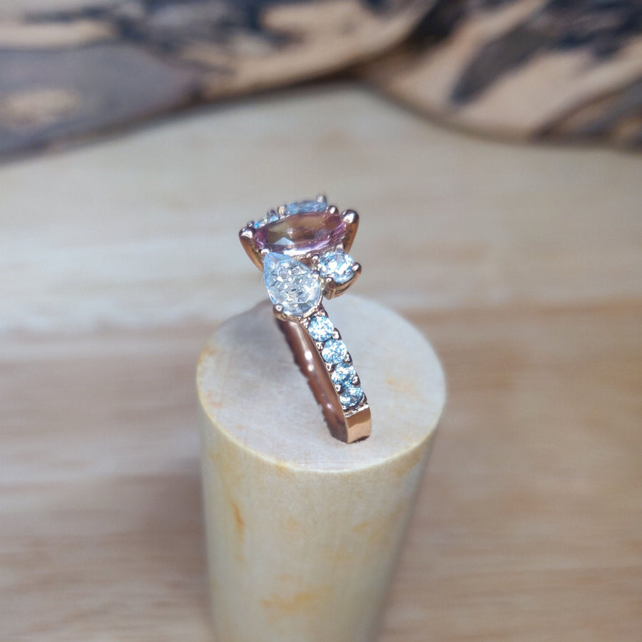 Top View of a Bi Colour Tourmaline and lab-grown diamond gold engagement ring on a wooden stand.
