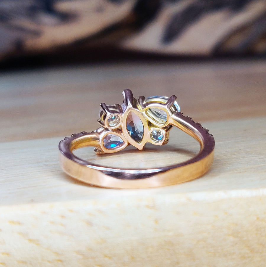 Bi Colour Tourmaline and lab-grown diamond gold engagement ring seen from the rear on a wooden bench.