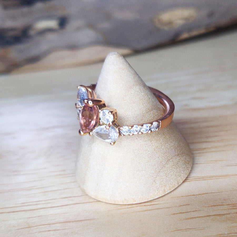 Side view of a Bi Colour Tourmaline and lab-grown diamond gold engagement ring on a wooden display cone