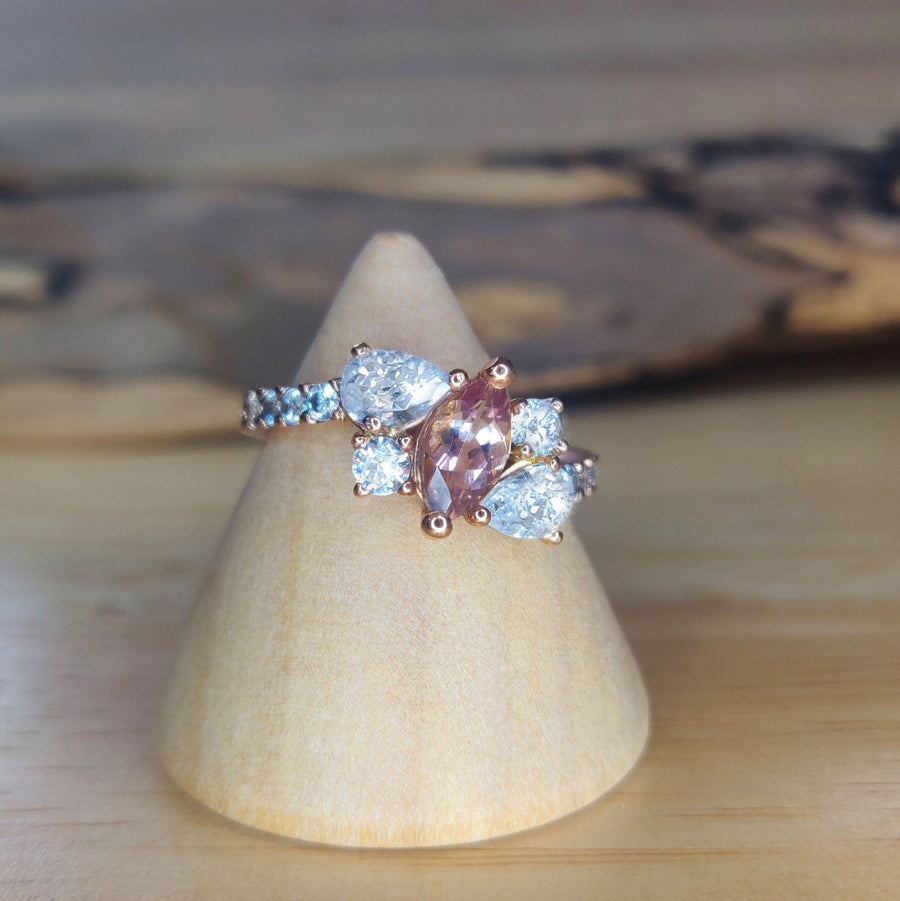 Bi Colour Tourmaline and lab-grown diamond gold engagement ring on a Wooden Cone on a bench.