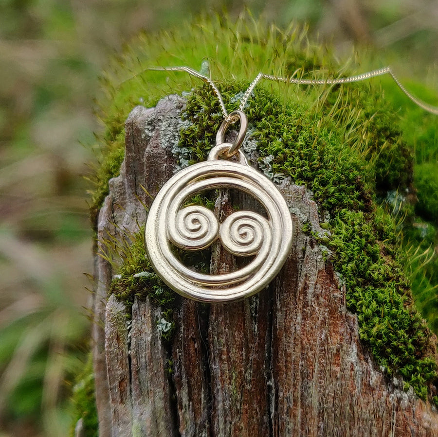 14k solid gold celtic knot necklace with equinox design in a nature setting.