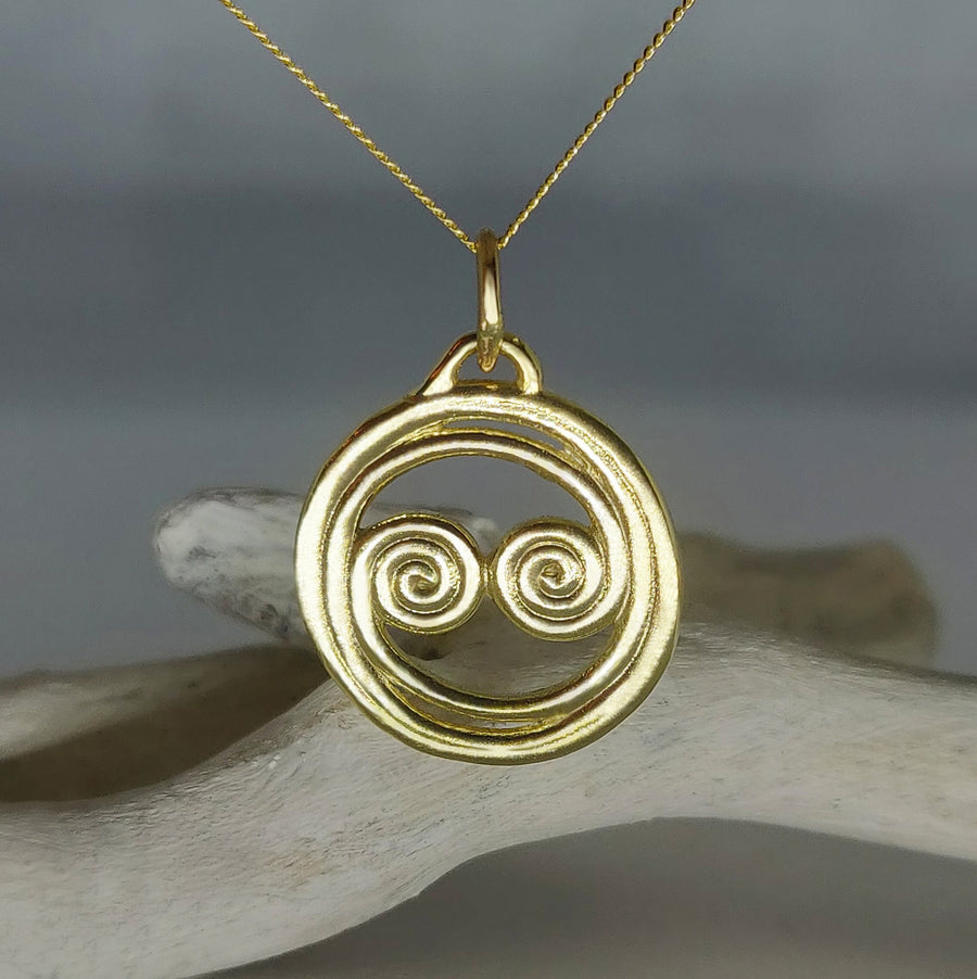 Image of a celtic spiral equinox pendant in 14ct yellow gold against a white background.