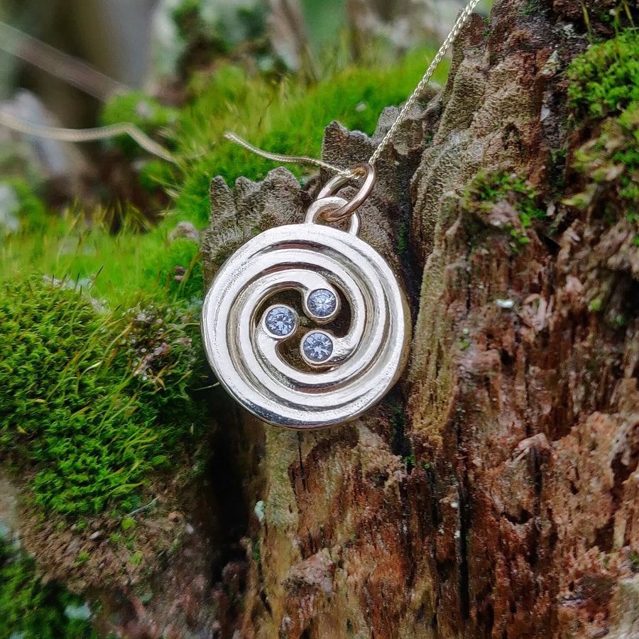 14k Diamond and Solid Gold Celtic Spiral Sun Necklace on a Natural Background.