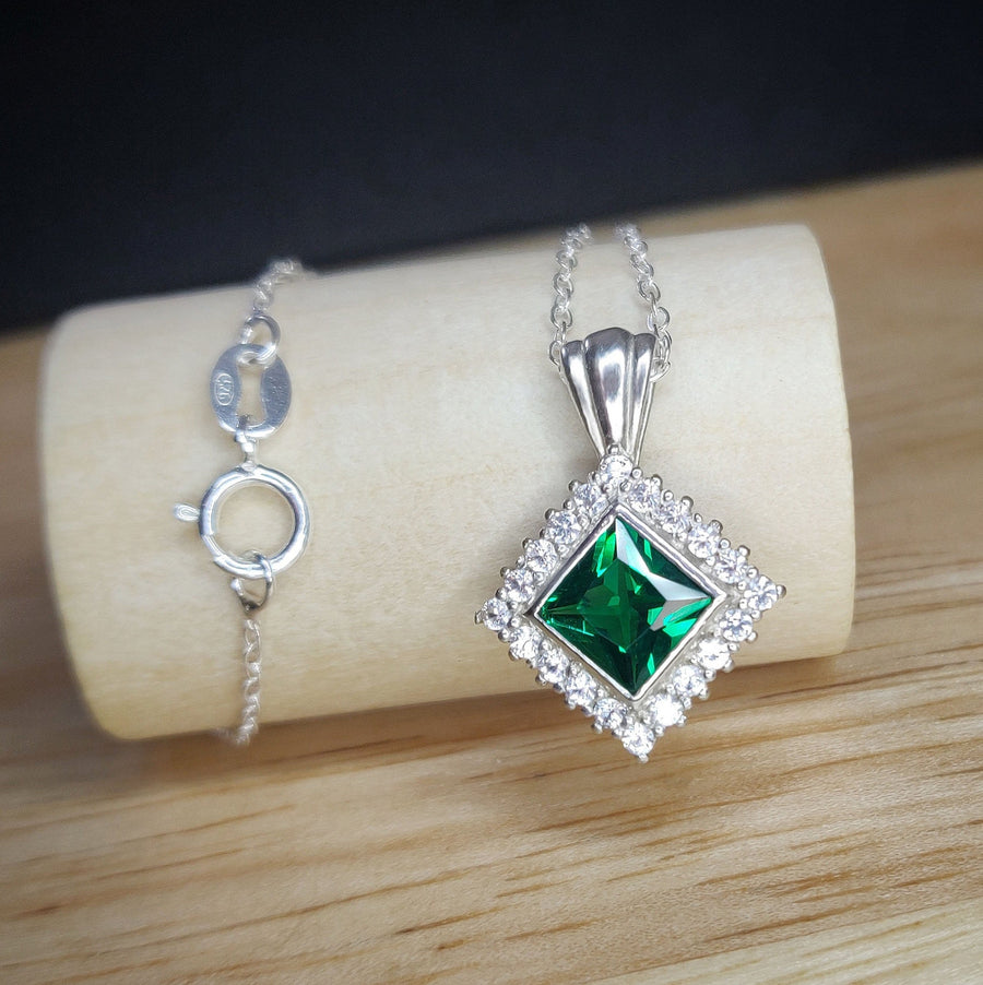 Princess Emerald and Diamond Halo Necklace on a wooden display