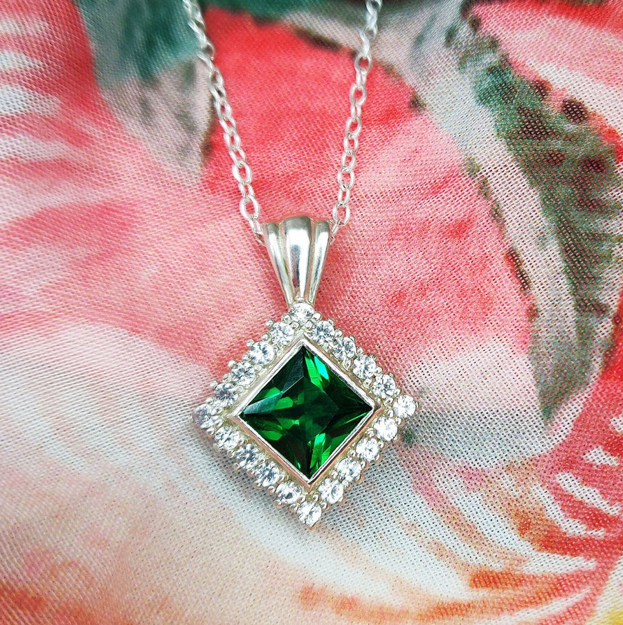 Princess Emerald and Diamond Halo Necklace on a cloth background