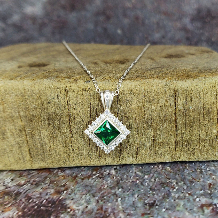 Princess Emerald and Diamond Cluster Necklace on a wooden block