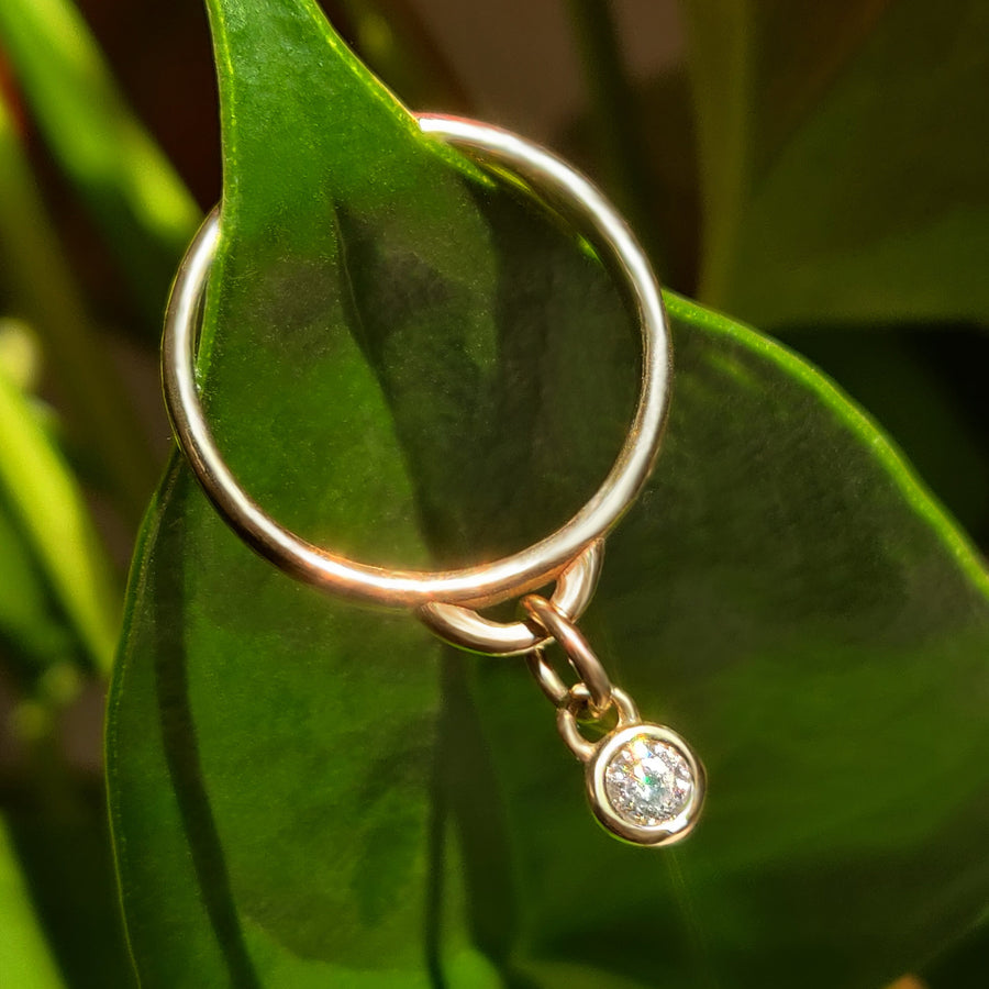 Diamond Bezel Ring with charm on a green background.
