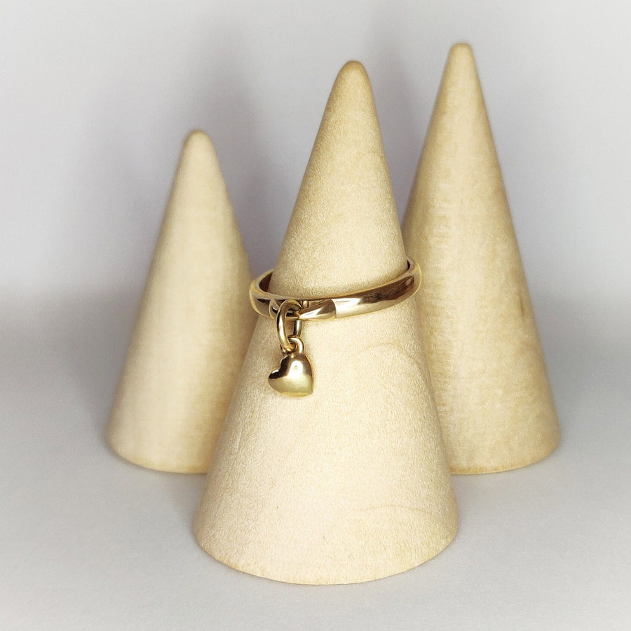 Solid gold heart drop ring dangling on a wooden display