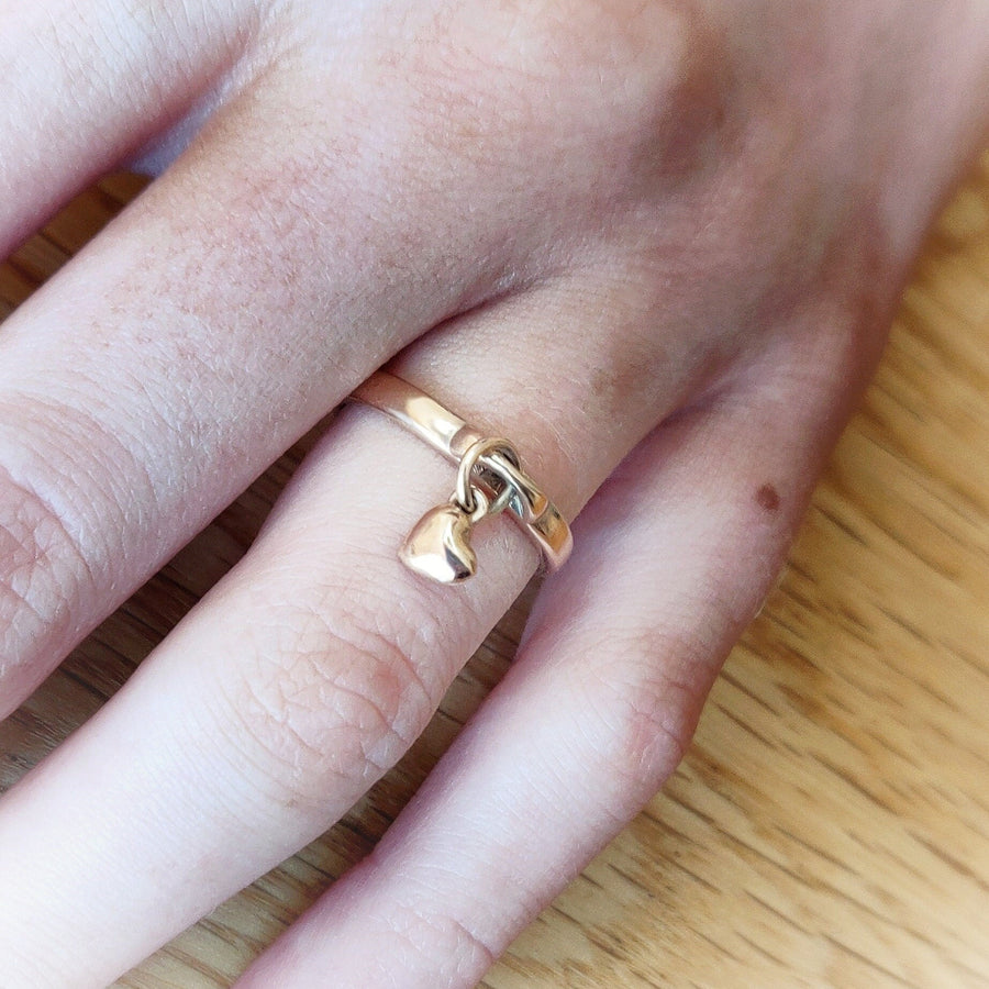 Close up of a heart charm ring being worn