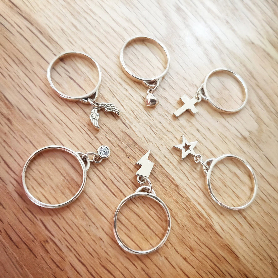 All six variations of solid gold charms rings on a wooden background.