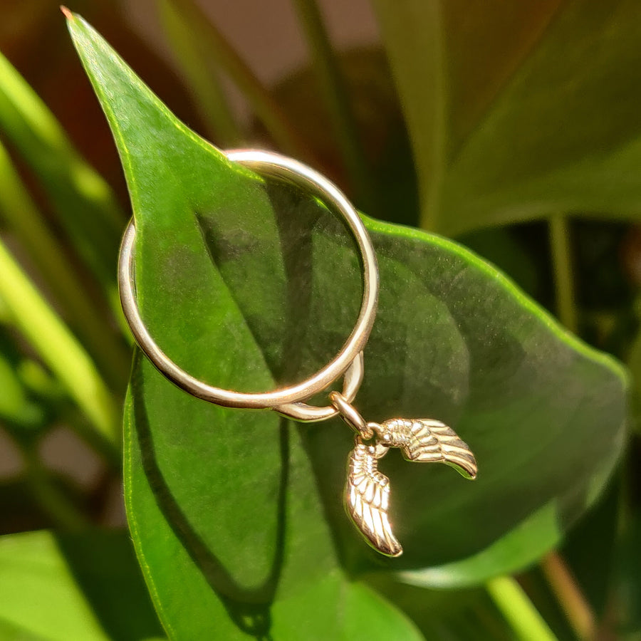 Gold Angel Wings Dangle Ring on a leaf.