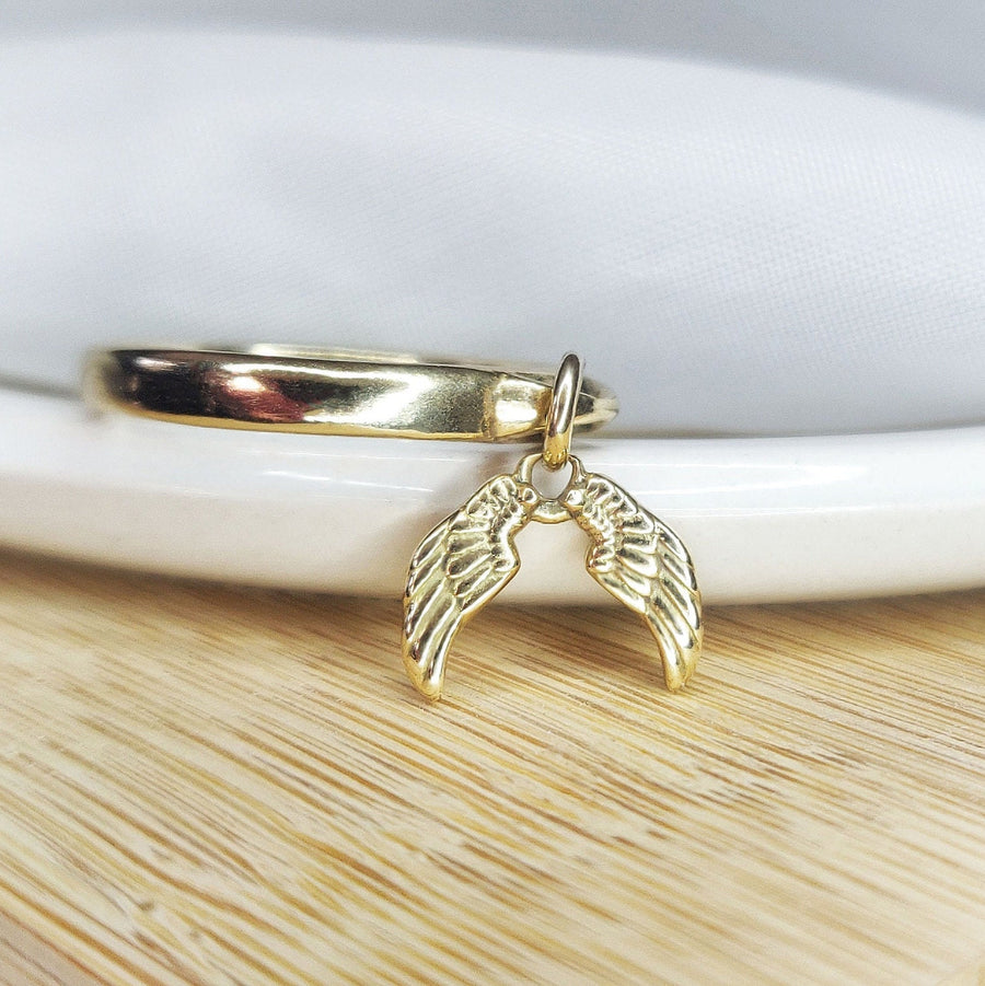 Solid gold angel wings drop ring in a dish