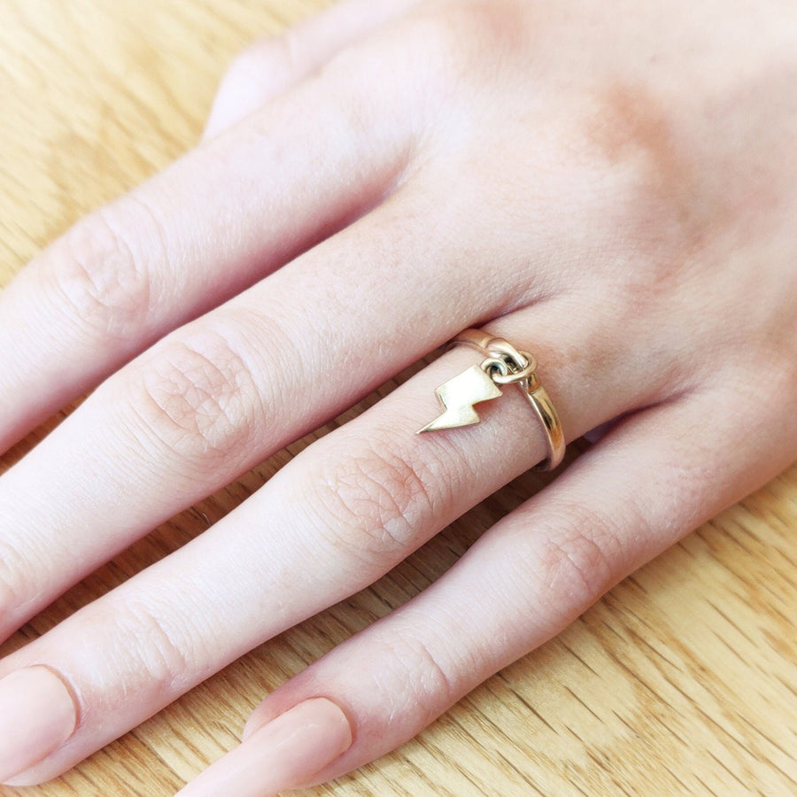 Hand wearing a solid gold lightning bolt charm ring