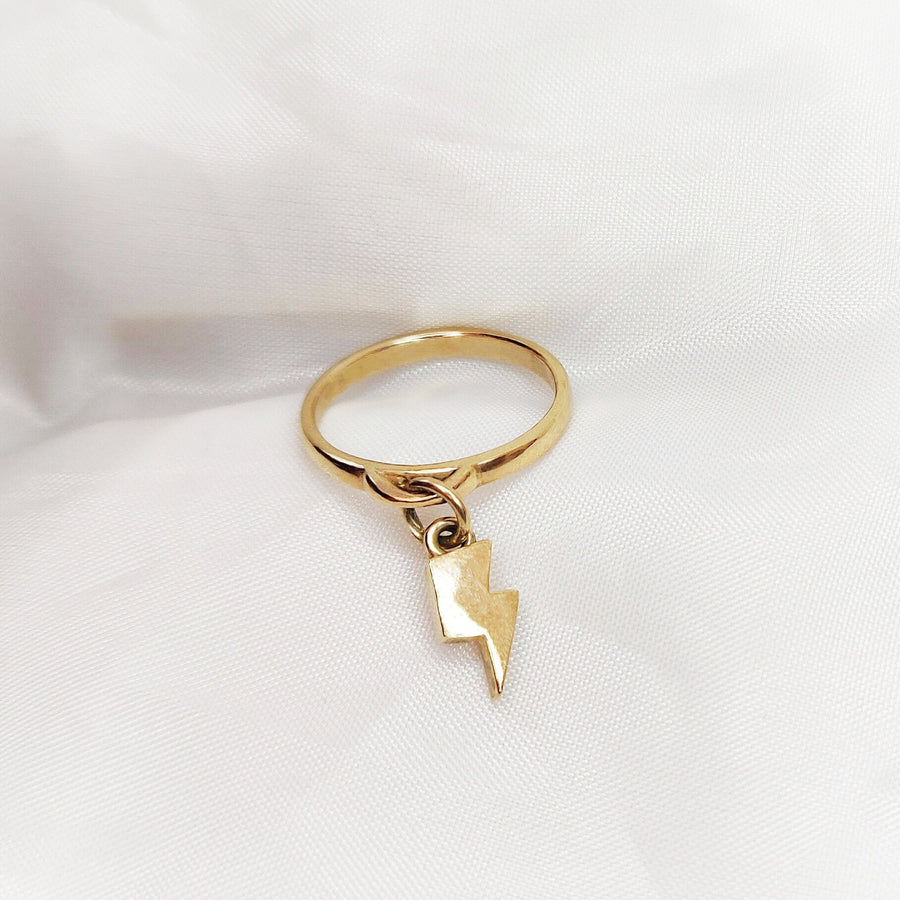 Solid gold lightning bolt charm ring on a white background