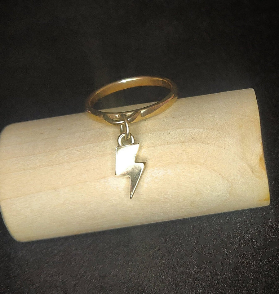 Gold Charm Ring with lightening bolt on a wooden block