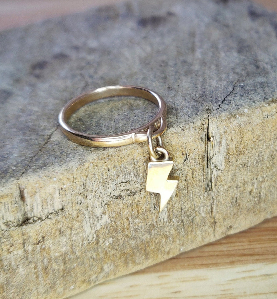 9ct gold dangle ring with lightning bolt on a wooden display