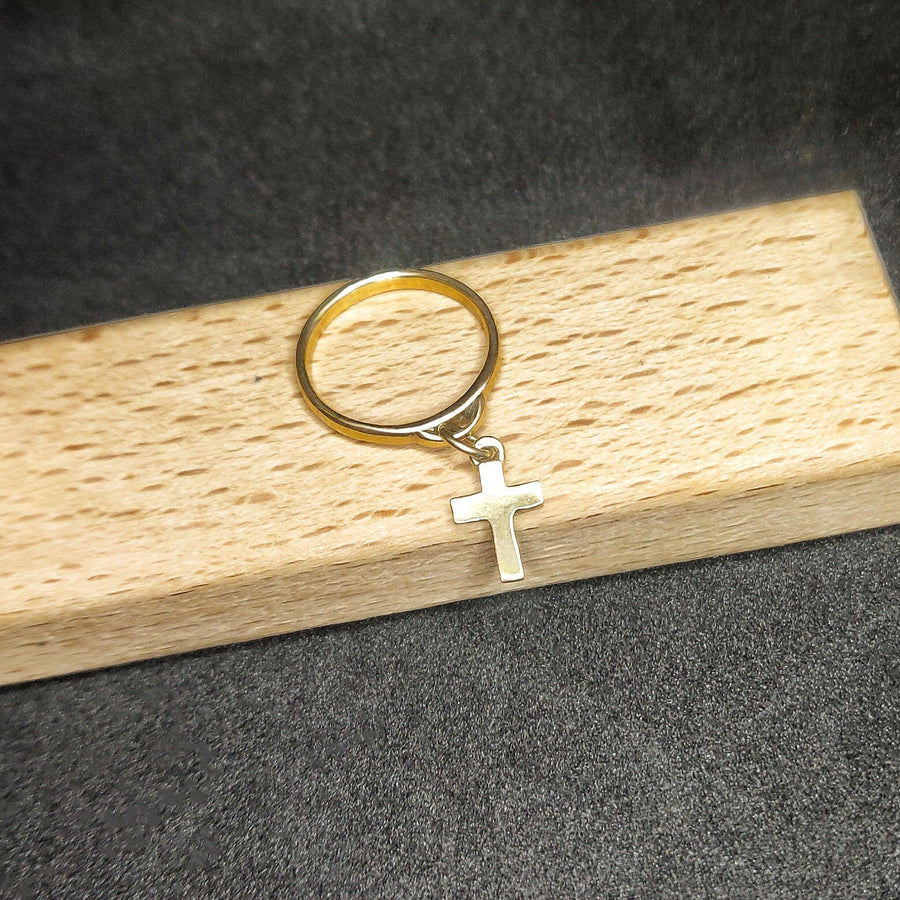 Solid gold charm ring with cross on a wooden display
