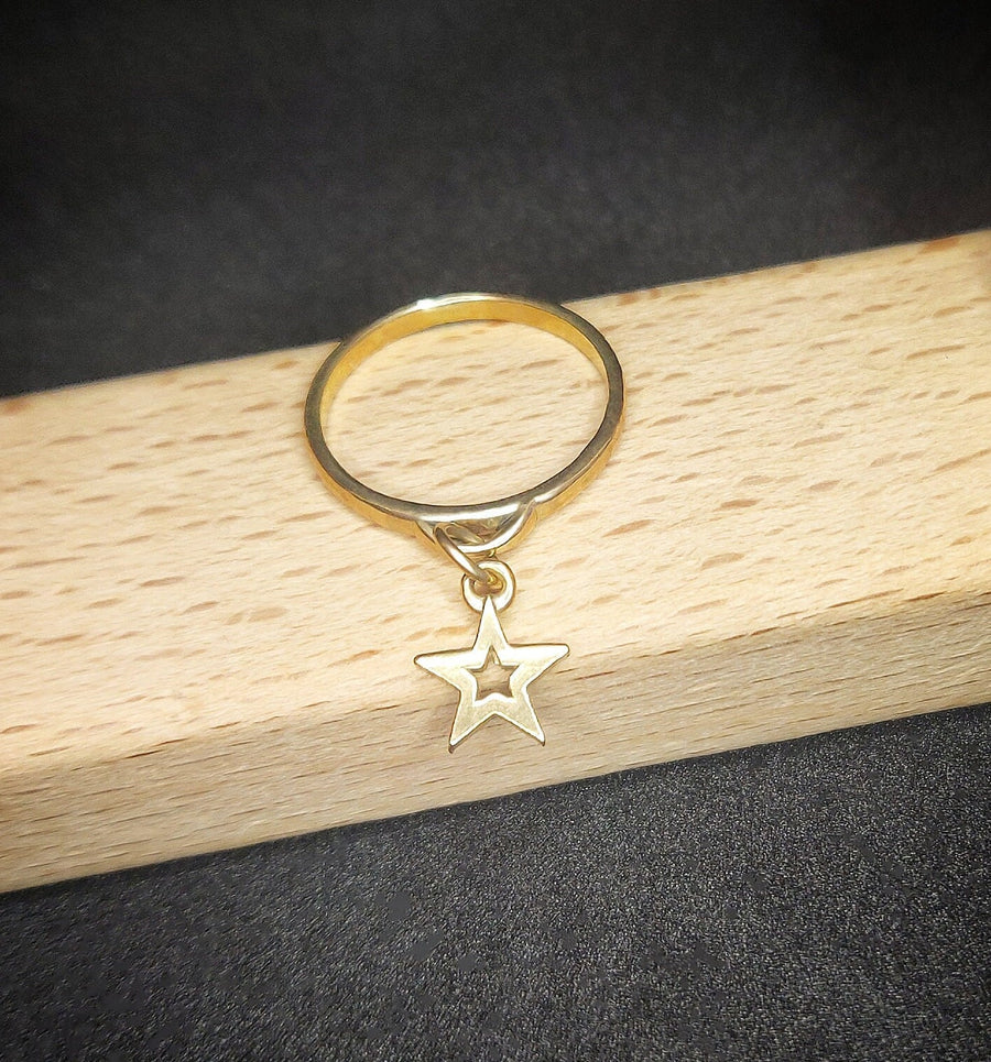 Wooden display with a solid gold dangly charm ring with a star.