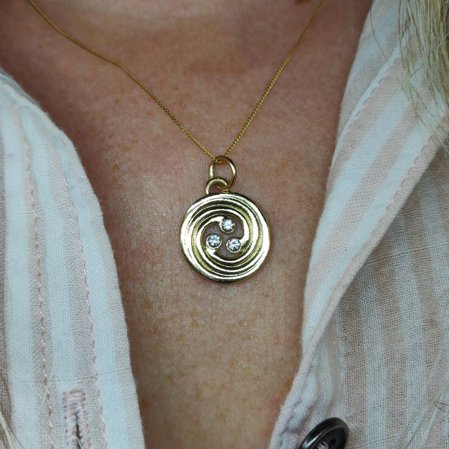 14k solid gold celtic spiral necklace with diamonds being worn.