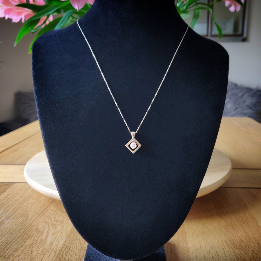 White Sapphire gold necklace hanging on a black bust.