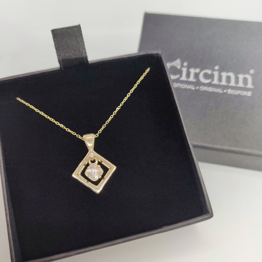 Gold square necklace with square gemstone in a branded jewellery box.