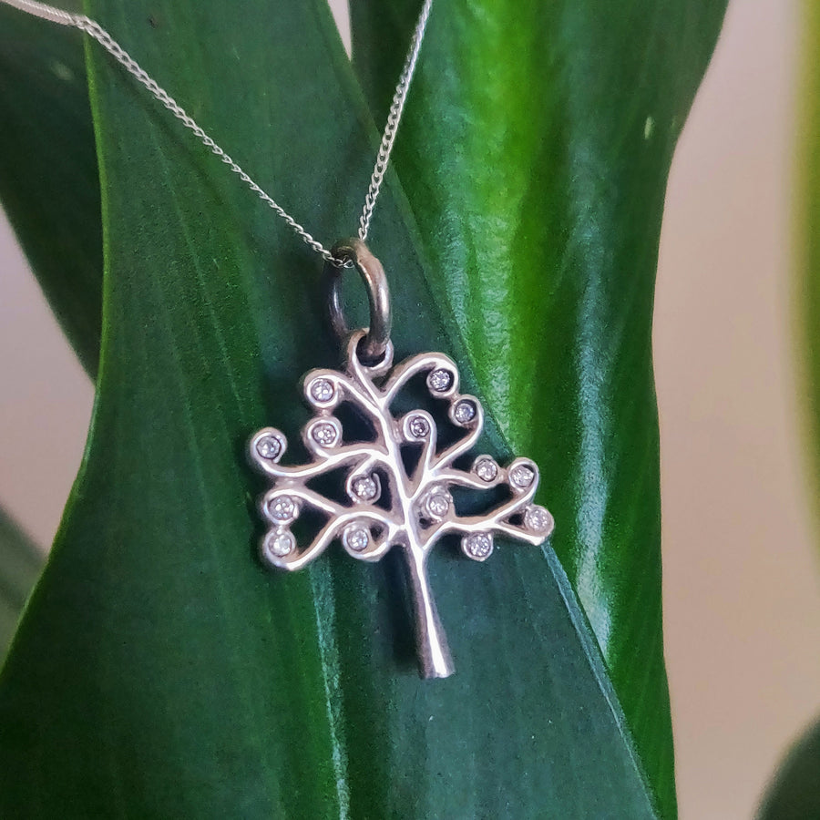 Solid gold yggdrasil tree of life pendant with diamonds on a plant.