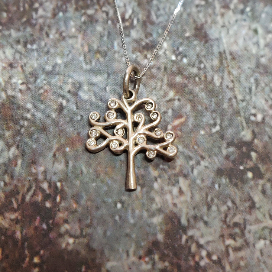 Gold and diamond tree of life necklace on a stone background.