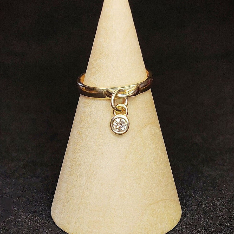 Solid Gold Bezel with VS Grade Diamond on a solid gold charm ring, displayed on a wooden cone