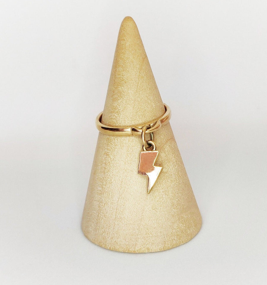 Solid gold lightning bold dangle ring on a wooden display