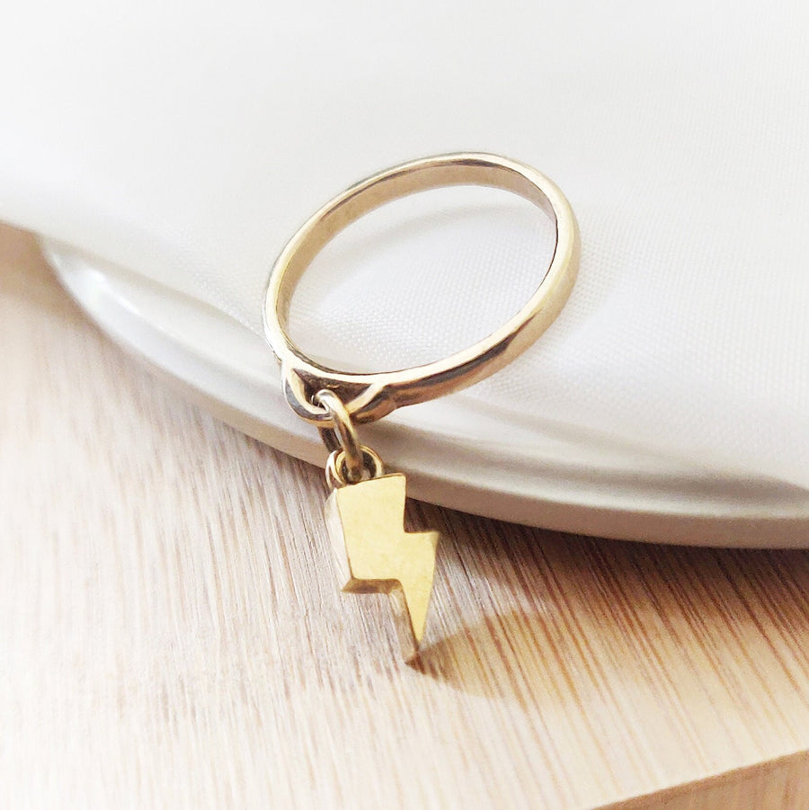 Solid Gold Lightning Bolt Charm Ring on a dish