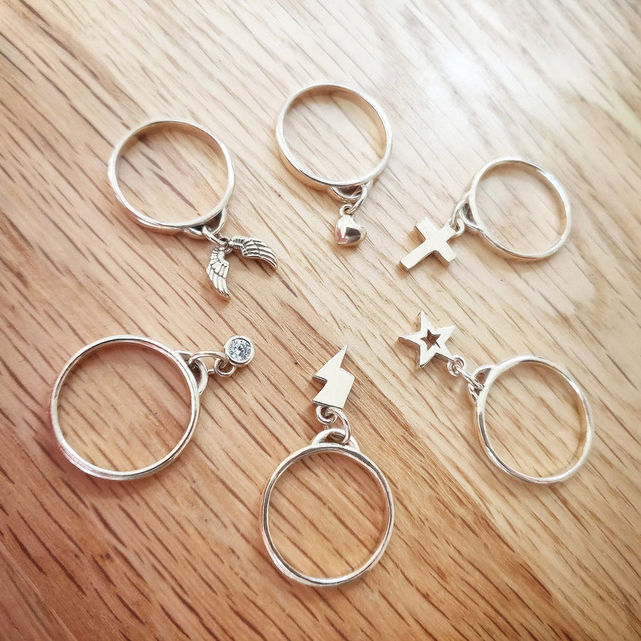 Selection of gold charm rings on a wooden background.