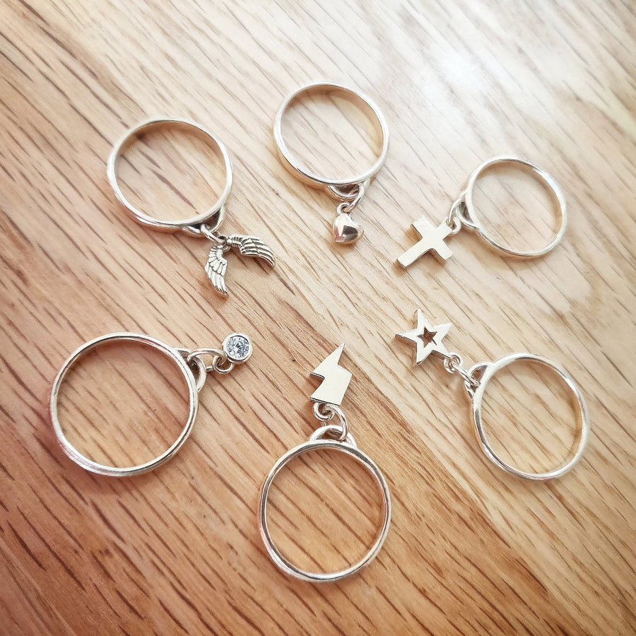 Selection of gold charm rings on a wooden background.