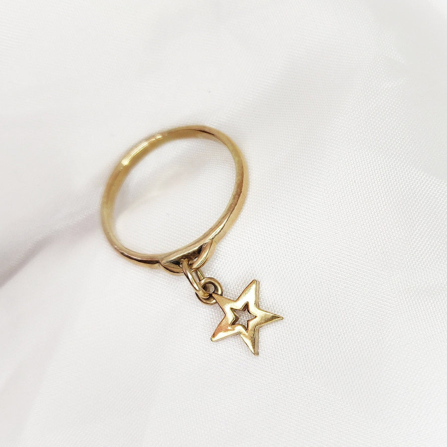 Star dangle ring in gold on a white background.