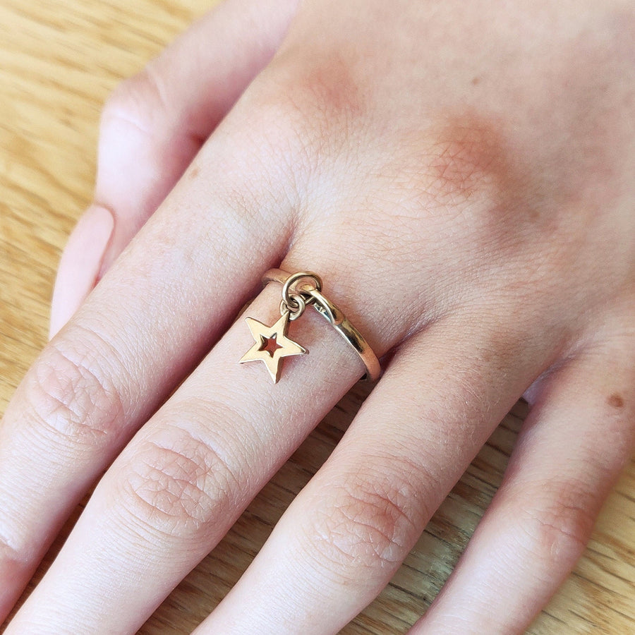 hand wearing solid gold star charm ring