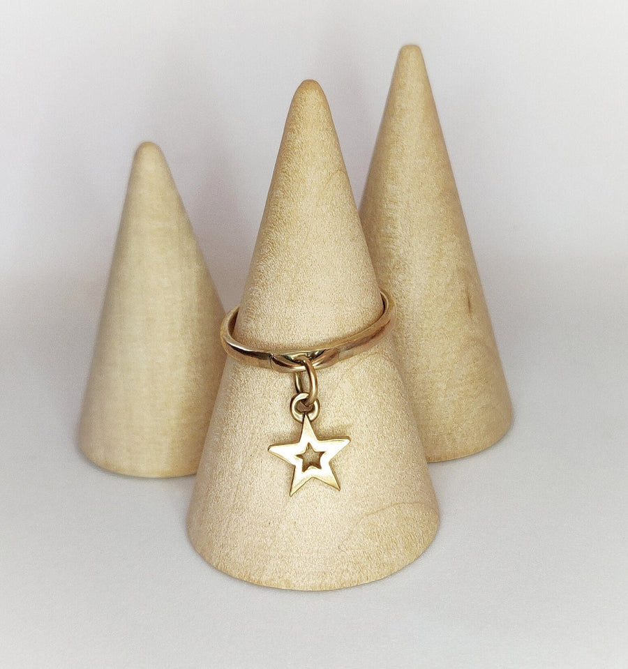 Wooden cone with a gold dangle ring with a solid gold star charm on a white background.
